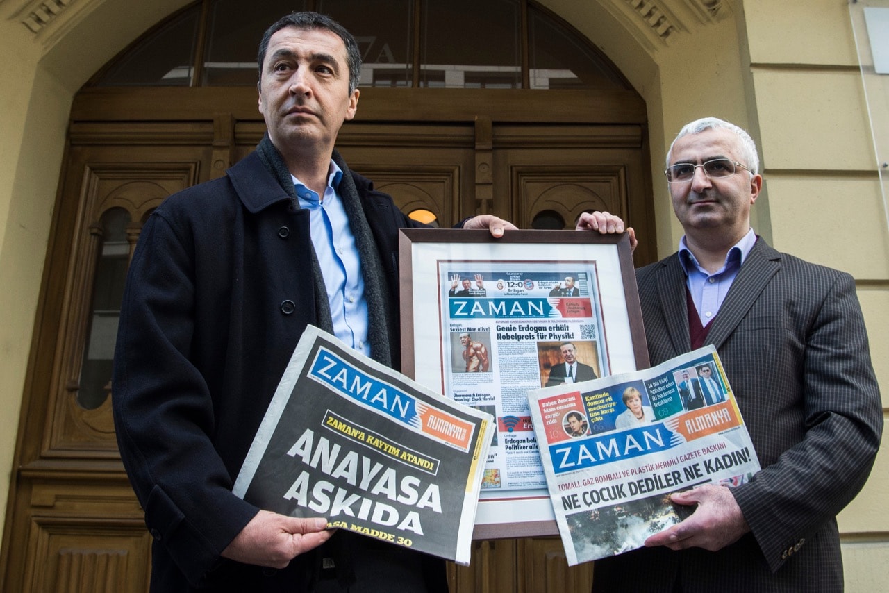 Suleyman Bag (R), chief editor of the German edition of Turkish daily "Zaman", and German Green Party co-leader Cem Oezdemir pose with the newspaper's last edition in Berlin, 7 March 2016, JOHN MACDOUGALL/AFP/Getty Images