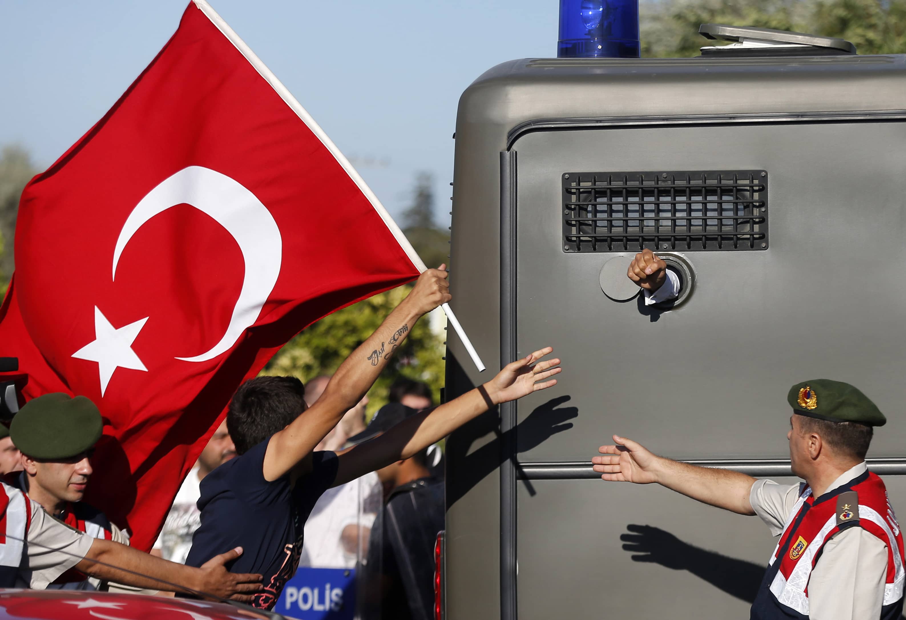 Protesters run after a prison van as an unidentified defendant sticks his fist out as he's driven to a courthouse in Silivri, 5 August 2013., Reuters/Murad Sezer