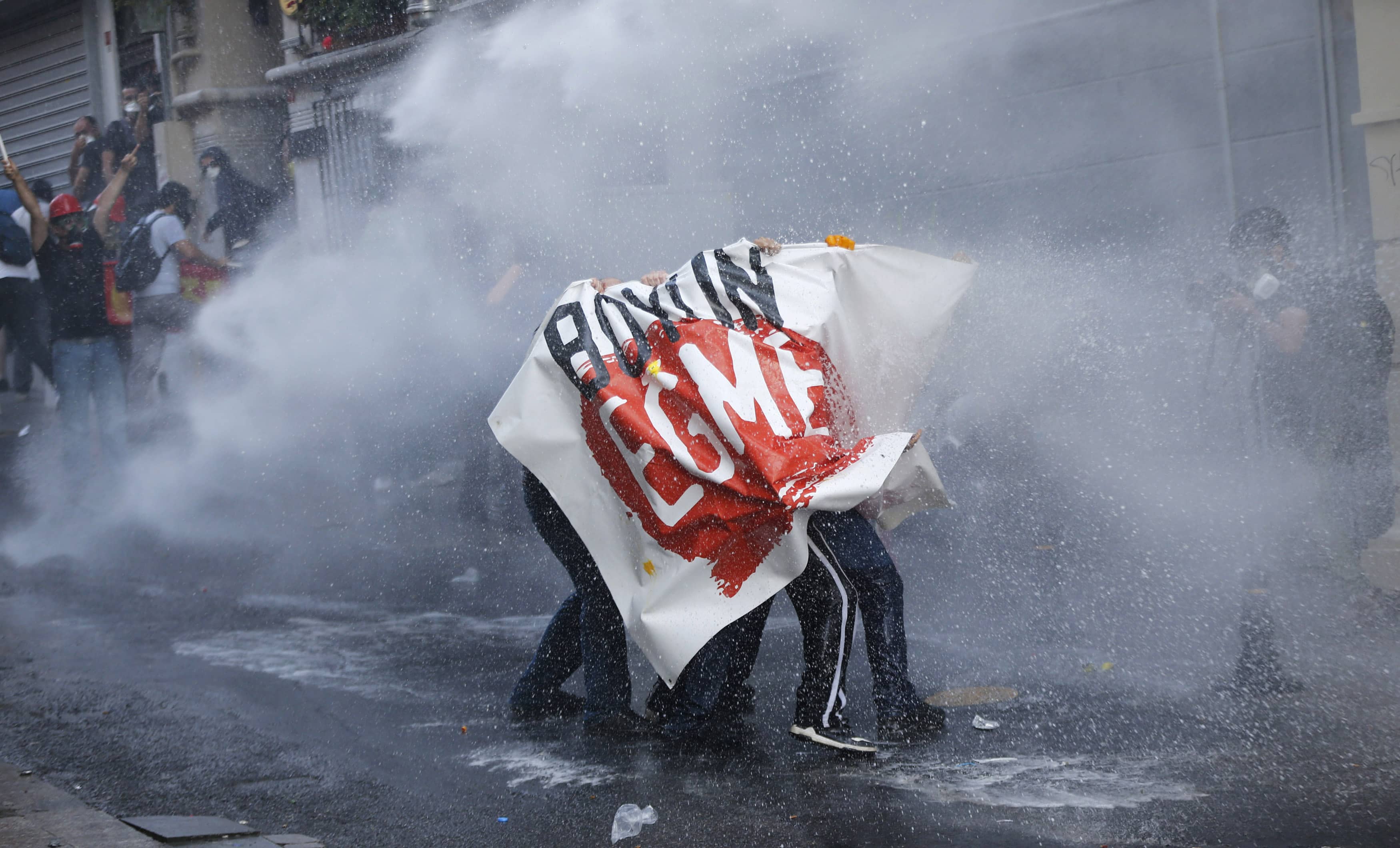 Demonstrators hold a banner reading, "Don't bow down", as riot police use water cannon to disperse them during a protest in central Istanbul July 6, 2013. , REUTERS/Murad Sezer