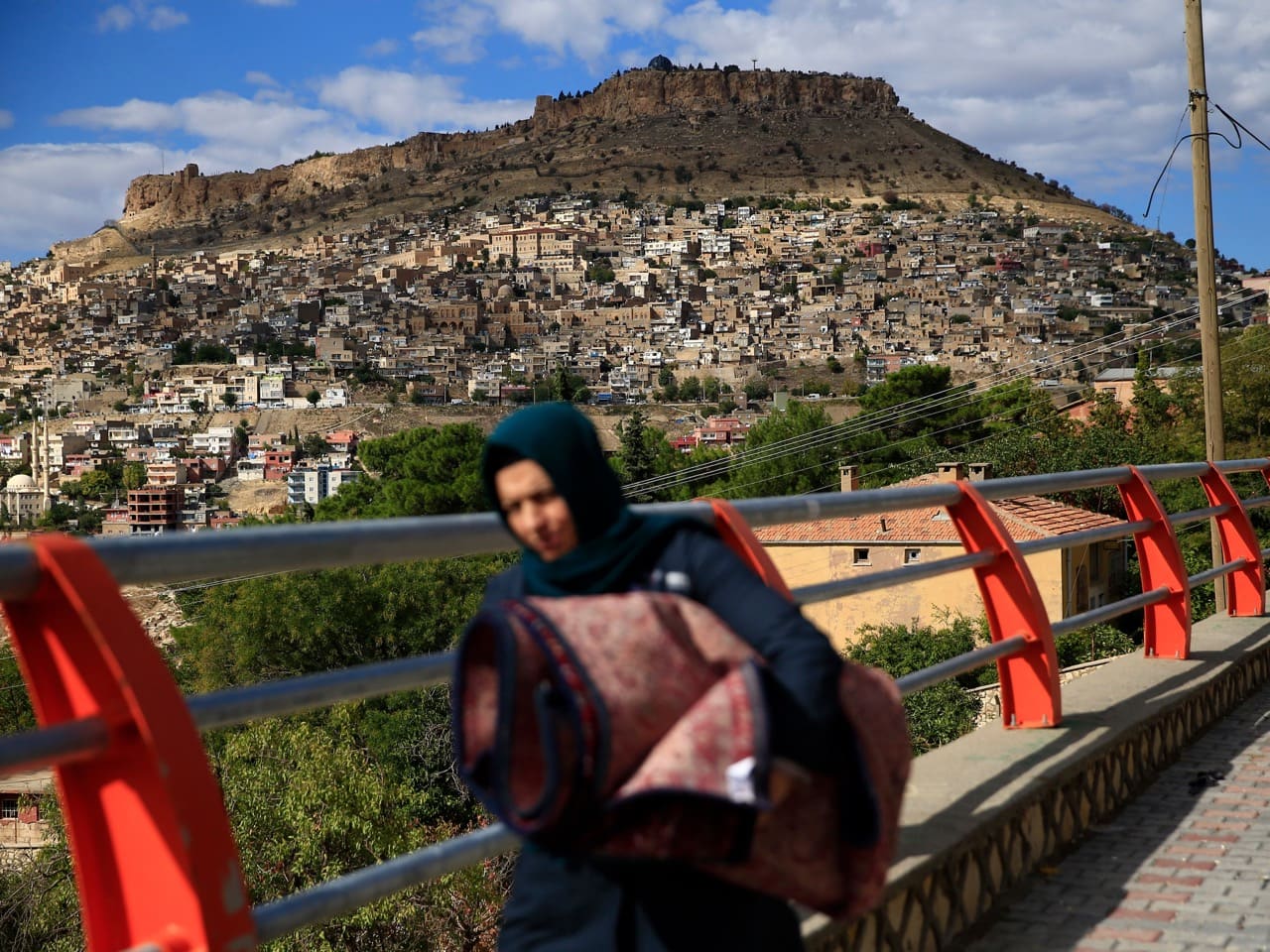 A woman walks, backdropped by the historic Mardin Castle in Mardin, in Turkey's predominantly Kurdish southeast, 1 November 2015, AP Photo/Lefteris Pitarakis