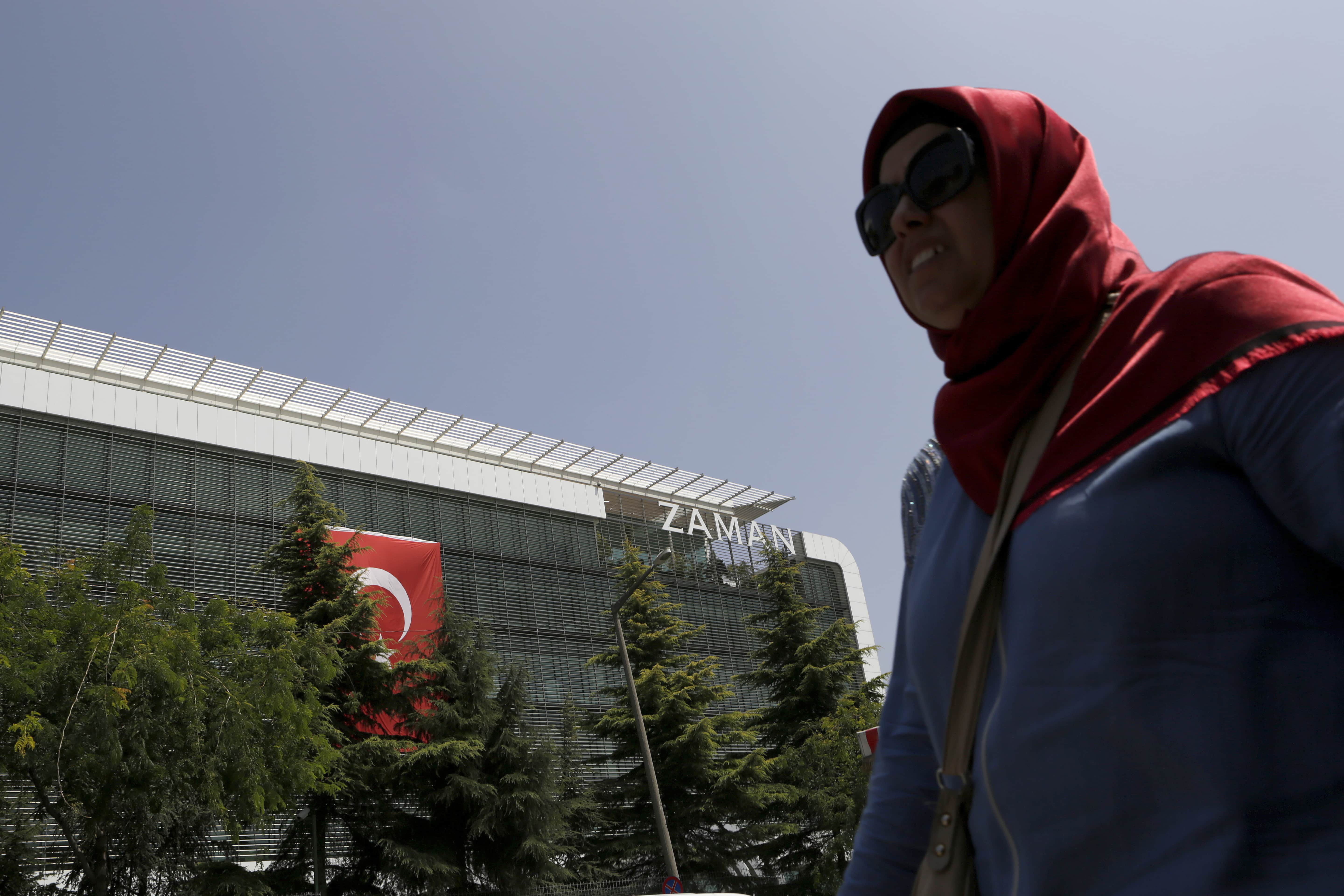 A woman walks past the headquarters of 'Zaman' newspaper, after being closed by the government in Istanbul, 28 July 2016, AP Photo/Petros Karadjias