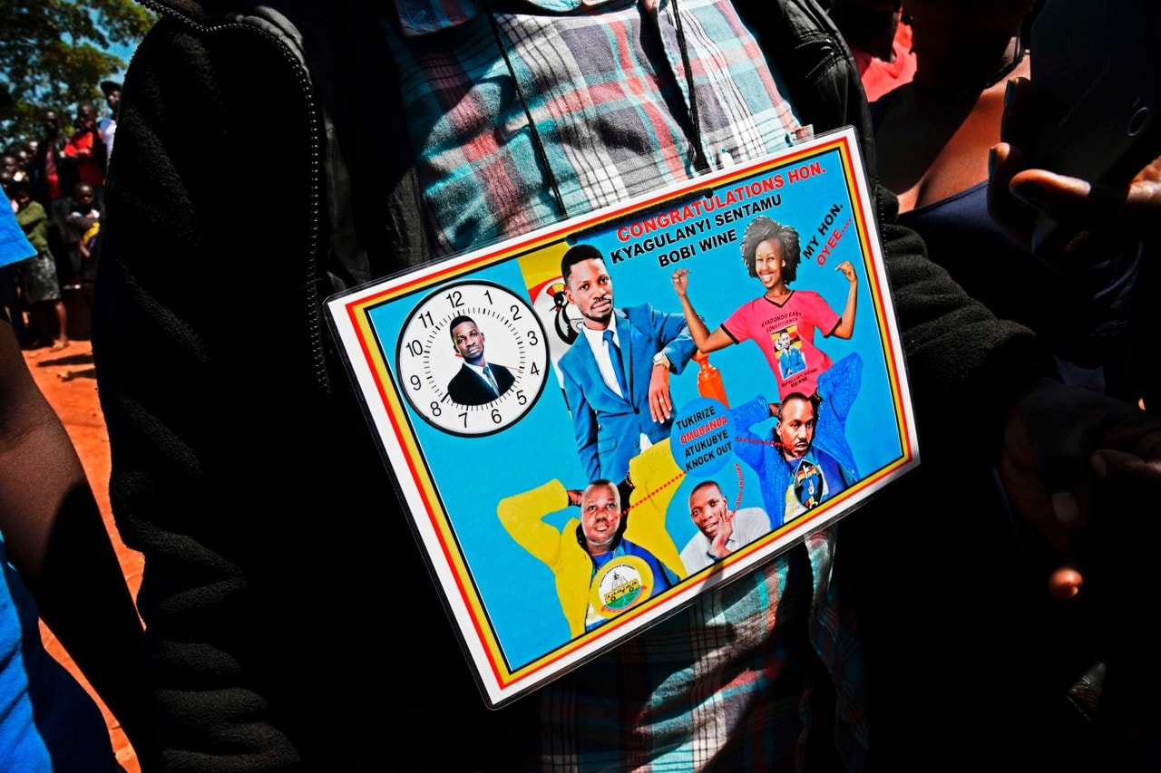 A supporter holds a political poster of musician turned politician, Robert Ssentamu Kyagulanyi, in a suburb of Kampala, Uganda, 30 June 2017, ISAAC KASAMANI/AFP/Getty Images