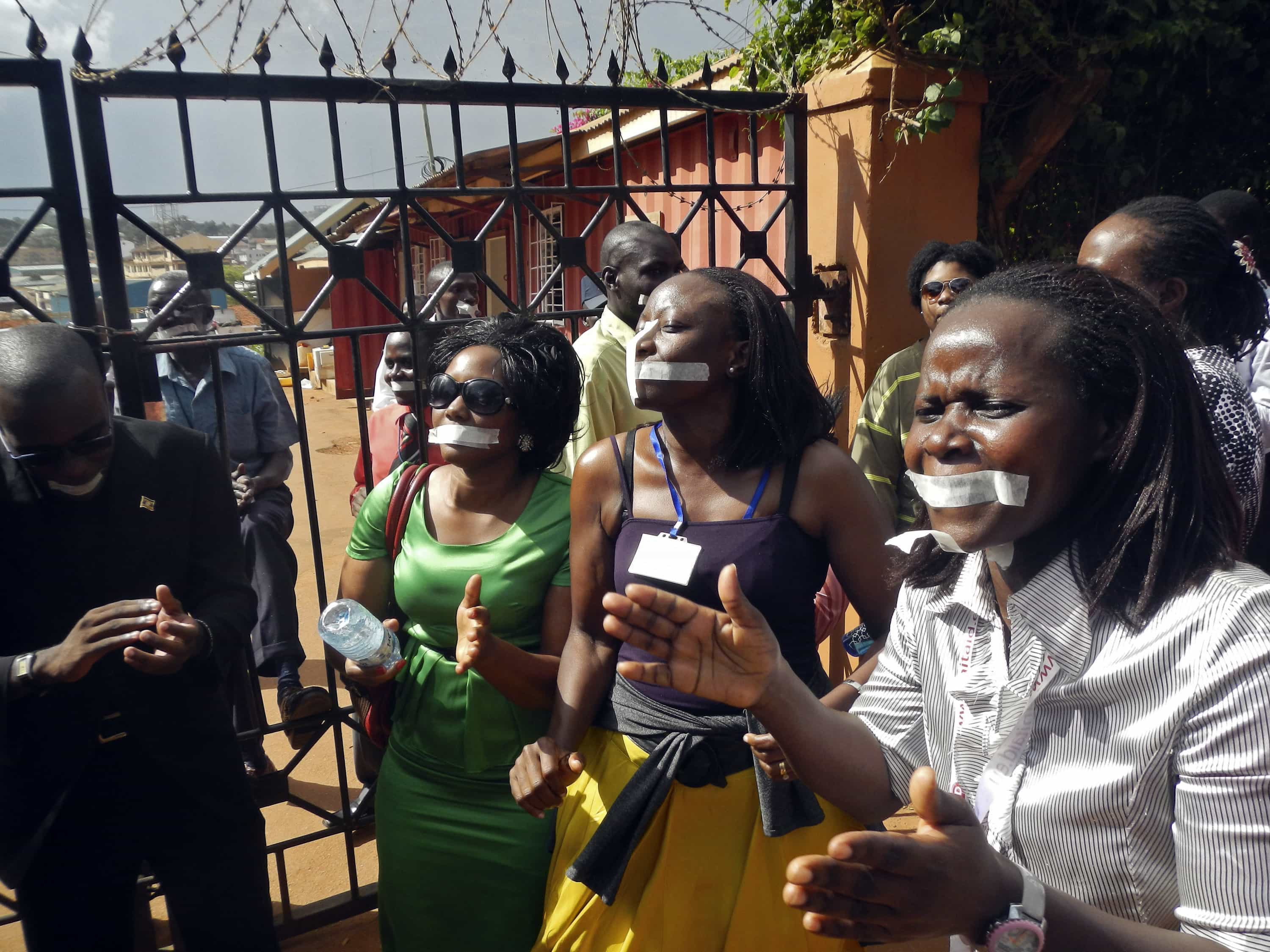 Employees of the Daily Monitor newspaper with their mouths taped shut, sing slogans during a protest against the closure of their premises by the Uganda government, outside their offices in Kampala, 20 May 2013, REUTERS/James Akena