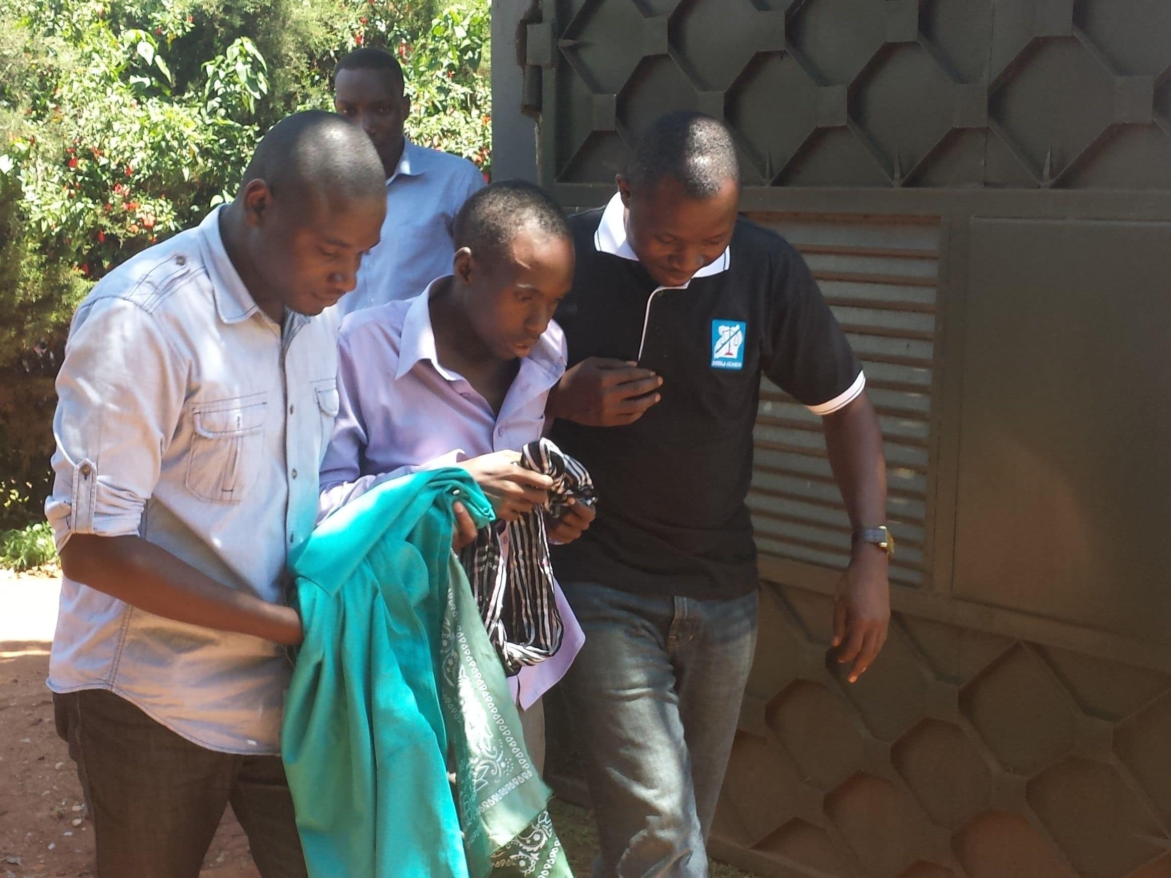 Ronald Ssembuusi (centre) is helped into the HRNJ-Uganda offices, by the organisation's staff, in Rubaga-Kampala, HRNJ-Uganda