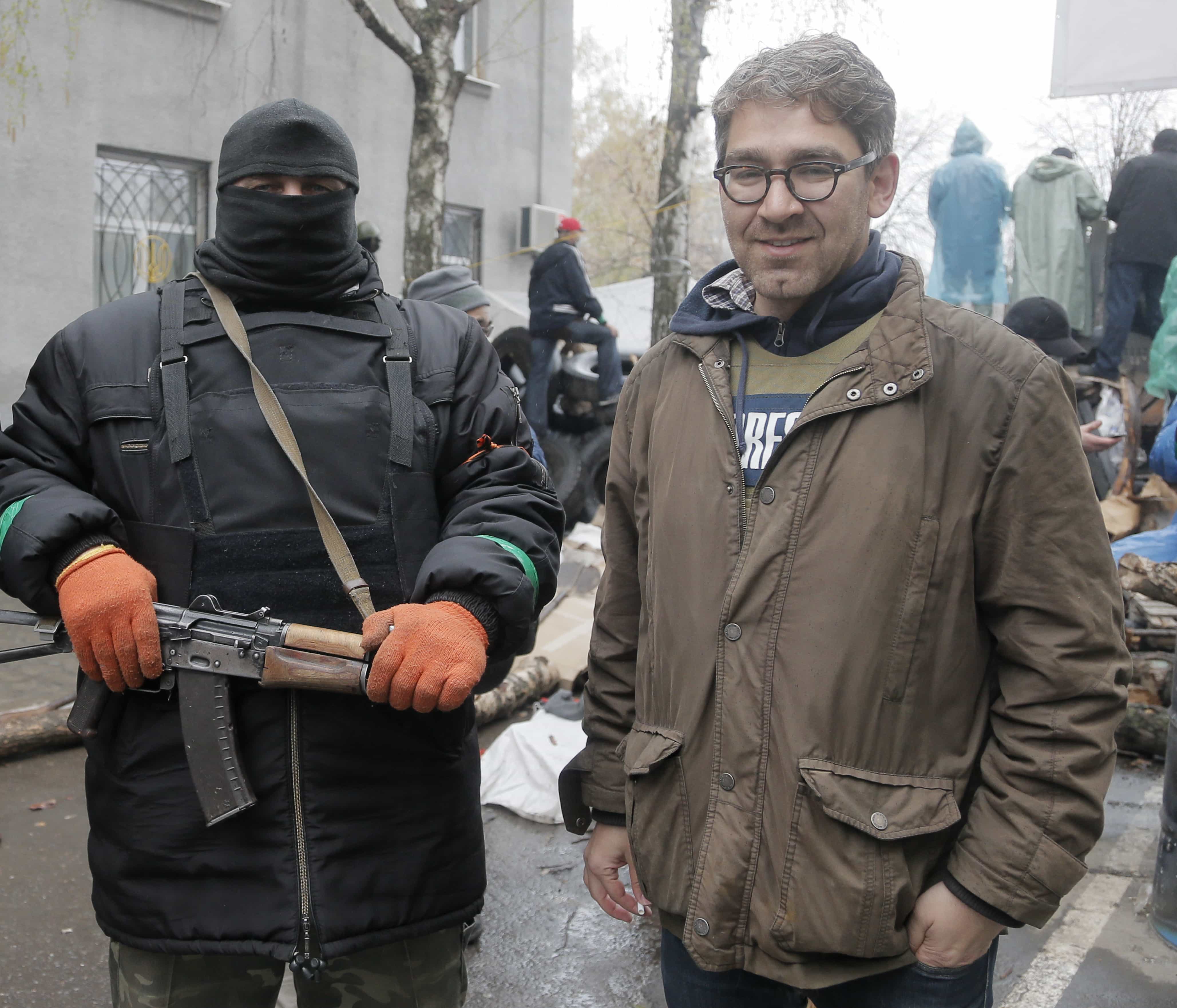 In this photo taken on 13 April 2014, U.S. reporter Simon Ostrovsky stands with a Pro-Russian gunman at a seized police station in the eastern Ukraine town of Slovyansk., AP Photo/Efrem Lukatsky
