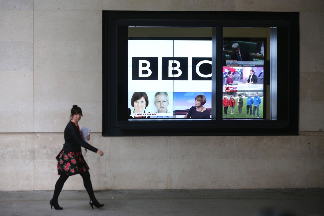 A woman walks past a bank of television screens displaying BBC channels at the BBC headquarters, in London, England, 12 November 2012, Oli Scarff/Getty Images