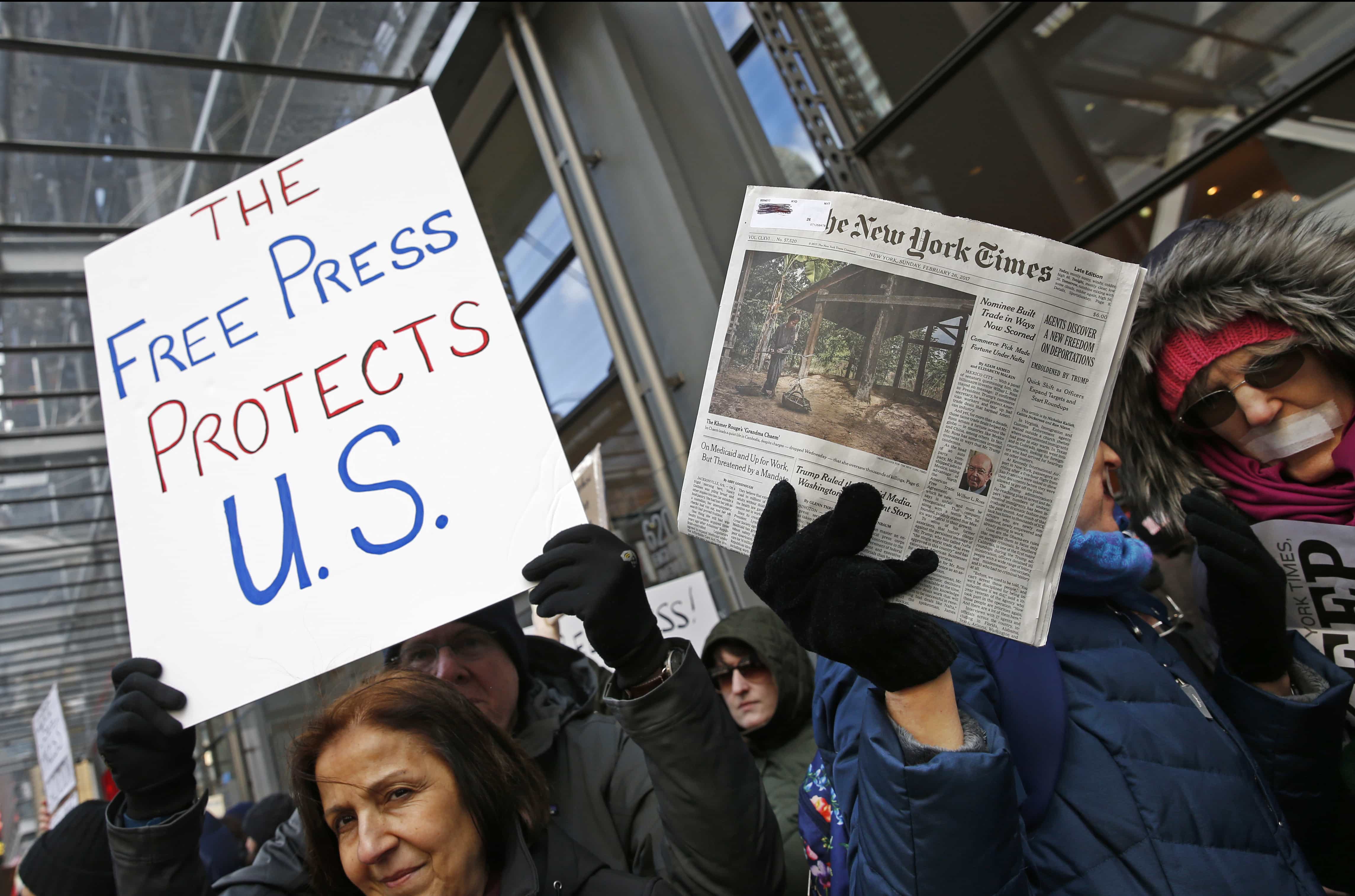 Protesters hold signs during a show of solidarity with the press in front of The New York Times building, 26 February 2017, in New York, AP Photo/Kathy Willens