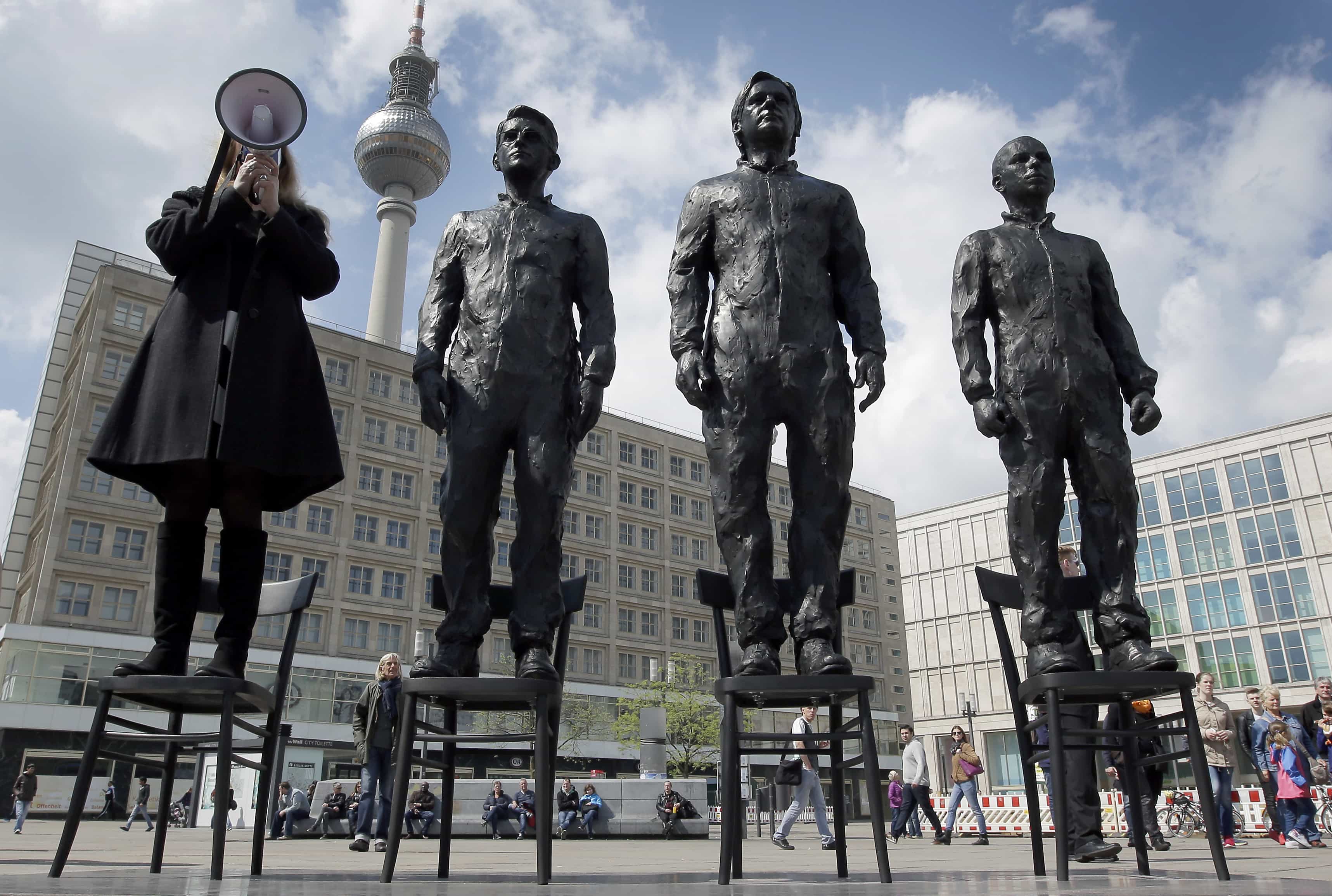 A women delivers a speech at the "Anything to Say?" statue in Berlin, Germany. The statue shows whistleblowers Chelsea Manning, Julian Assange and Edward Snowden., AP Photo/Michael Sohn