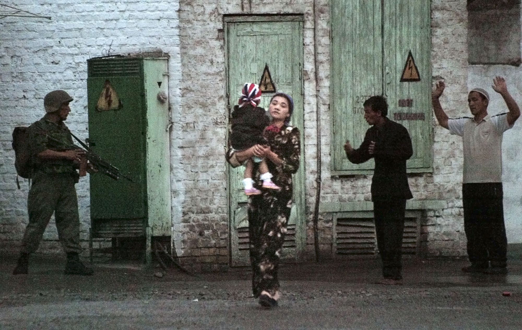In this 13 May 2005 file photo, a local resident carrying a child, walks by a soldier during the uprising in the city of Andijan, Uzbekistan, AP Photo/ Efrem Lukatsky, File