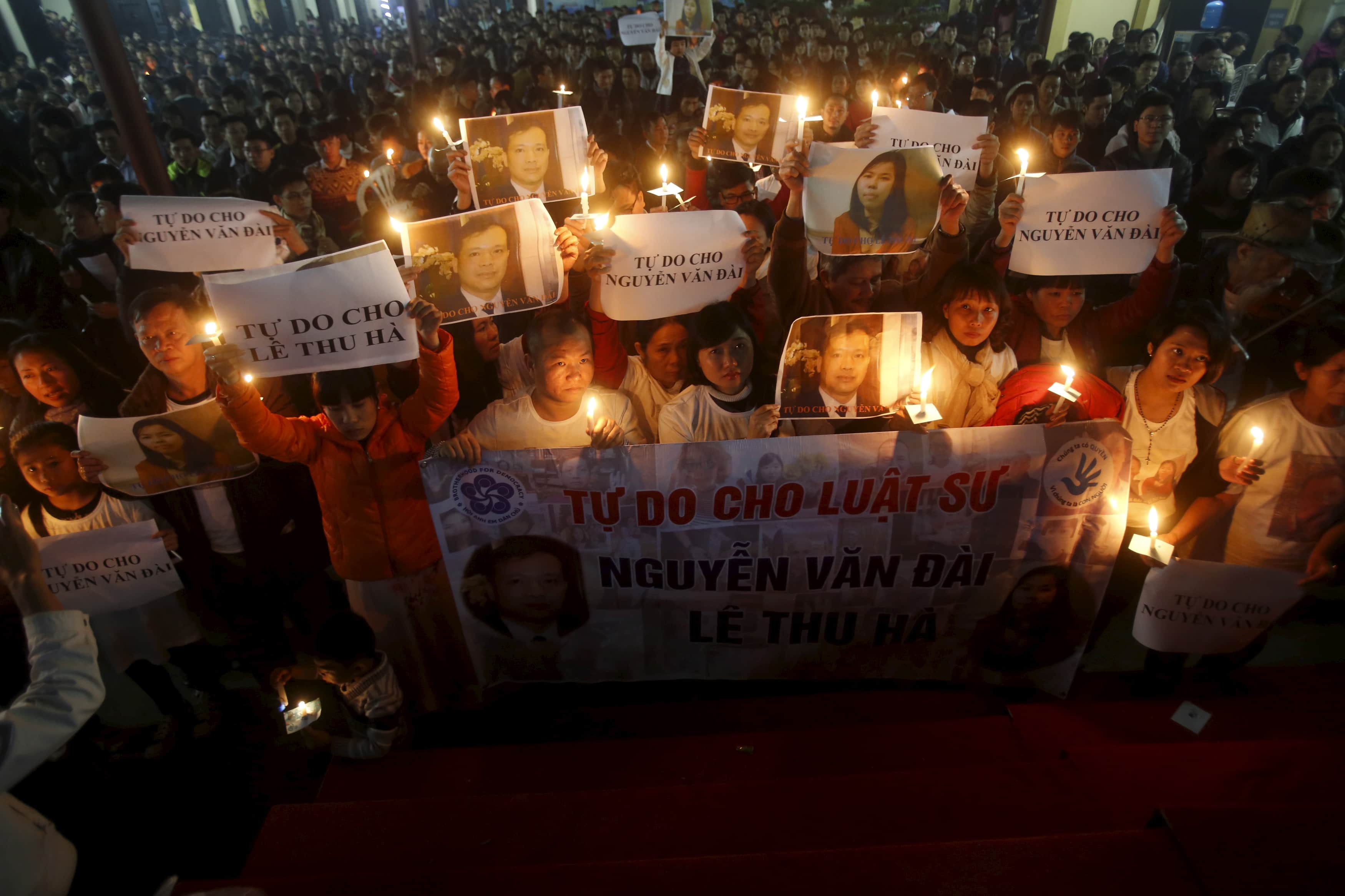 Vu Minh Khanh (C) holds an image of her husband Nguyen Van Dai during a mass prayer for Dai and his assistant in Hanoi, 27 December 2015. Dai was badly beaten by unknown attackers and subsequently arrested for anti-state "propaganda", REUTERS/Kham