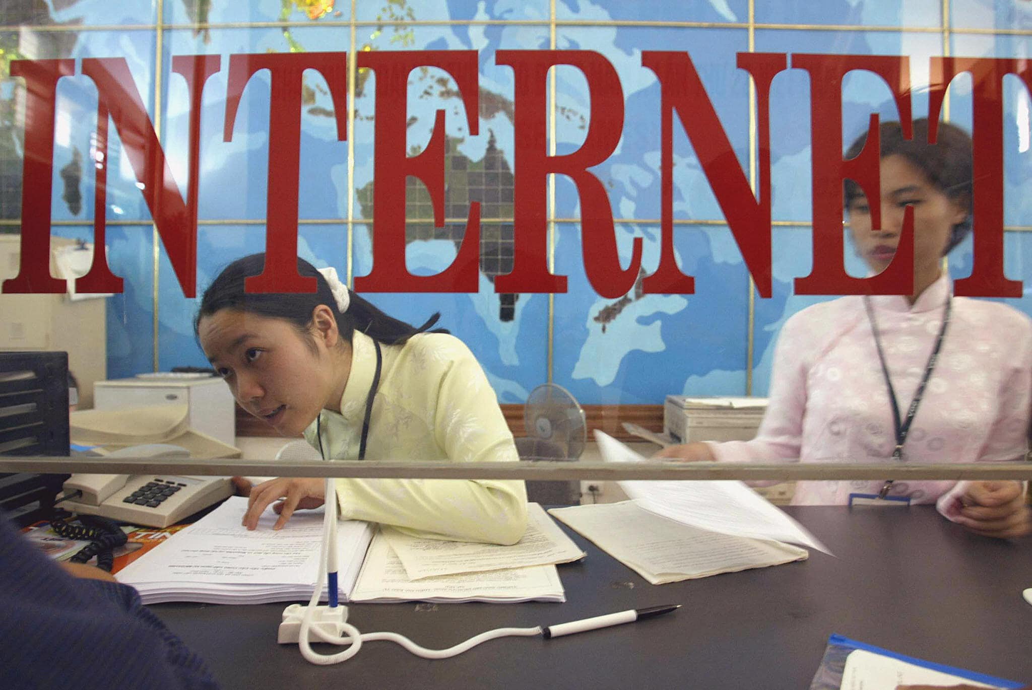A post office employee explains to a customer how to subscribe to a new high-speed internet service in Hanoi, Vietnam, 1 July 2003, HOANG DINH NAM/AFP/Getty Images
