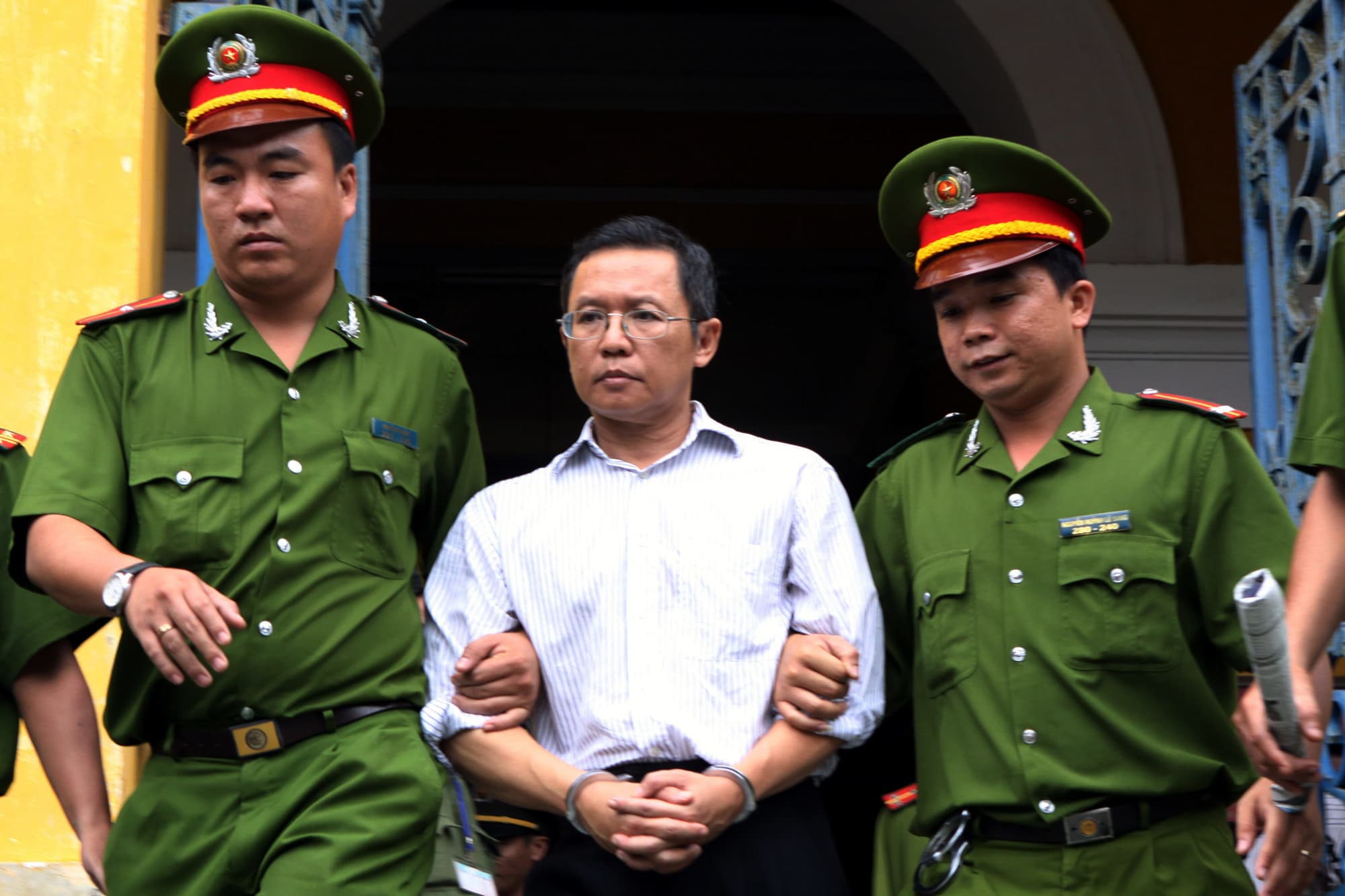 Police officers escort French-Vietnamese math professor Pham Minh Hoang out of a courthouse in Ho Chi Minh City, Vietnam, 10 August 2011, AP Photo/Vietnam News Agency, Hoang Hai