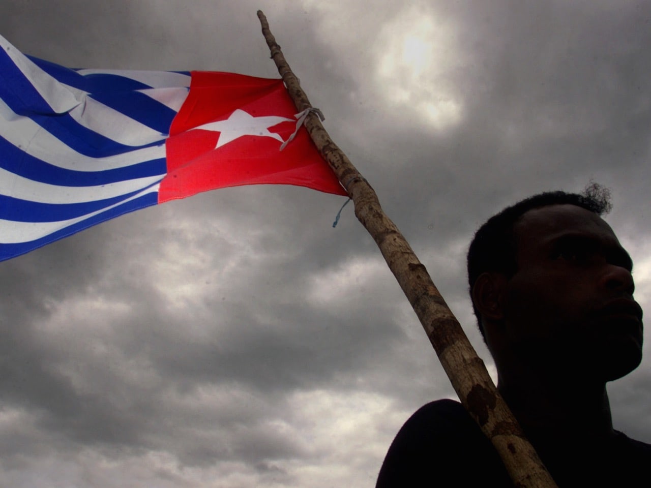 In this 17 November 2001 file photo, a Papuan holds the Morning Star independence flag during the funeral of a prominent independence leader in Sentani, West Papua, REUTERS/Darren Whiteside