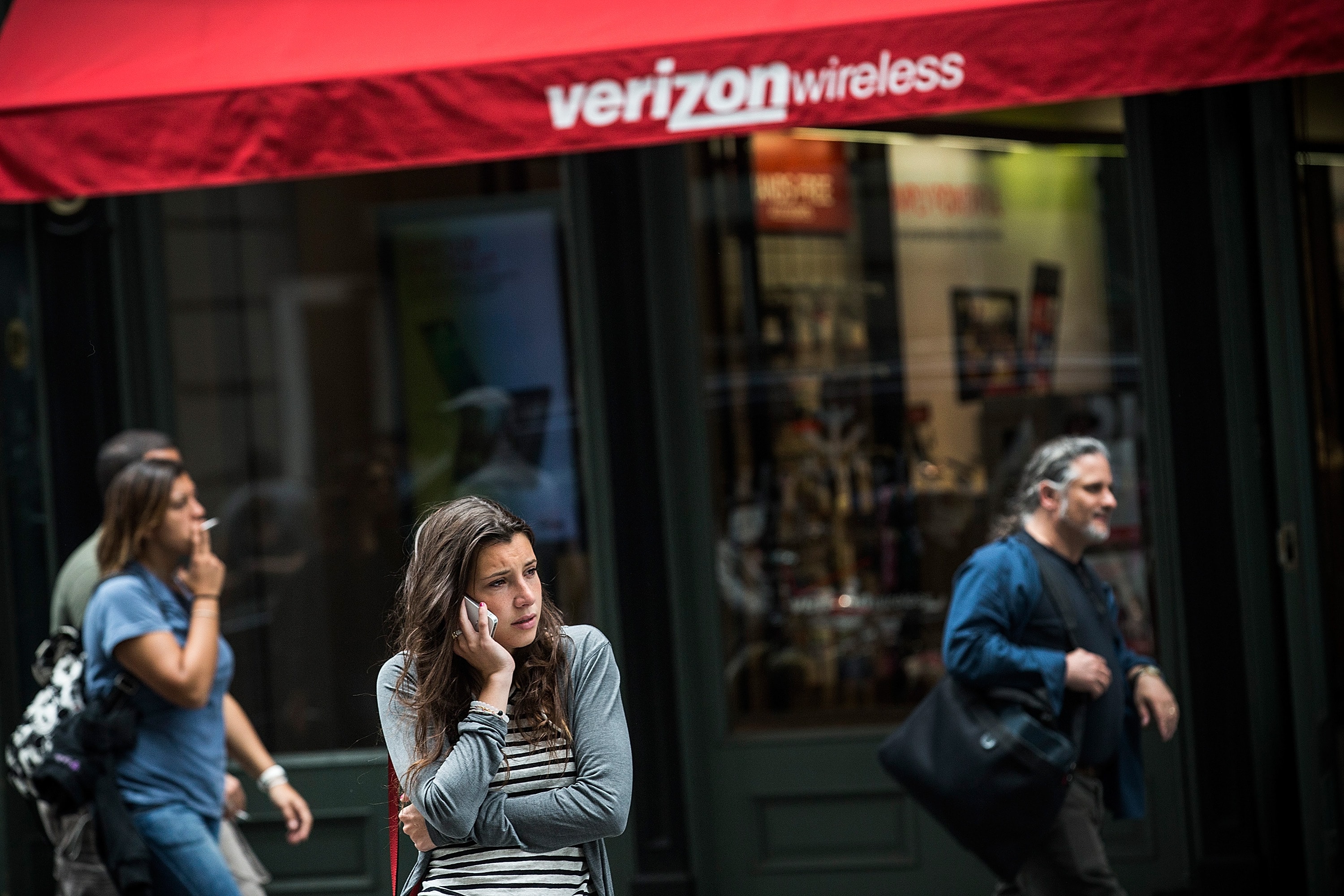 A woman uses her phone in front of a Verizon Store, one of several telecom companies police could force to disclose customer location and data under the Kelsey Smith Act, New York, United States, 2013, Andrew Burton/Getty Images