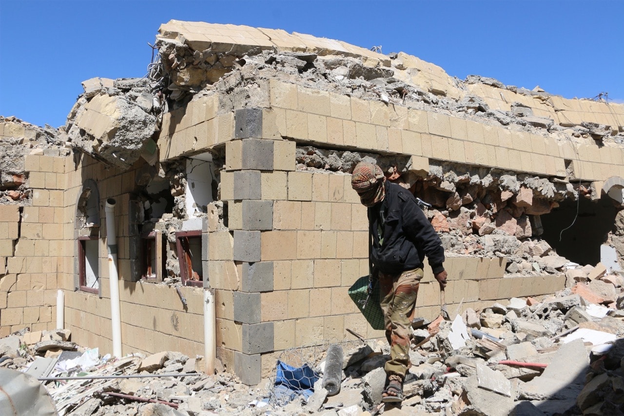 A man walks past debris of the state radio and television buildings after a Houthi attack in Taiz, Yemen, 23 December 2015, Abdulnasser Seddek/Anadolu Agency/Getty Images