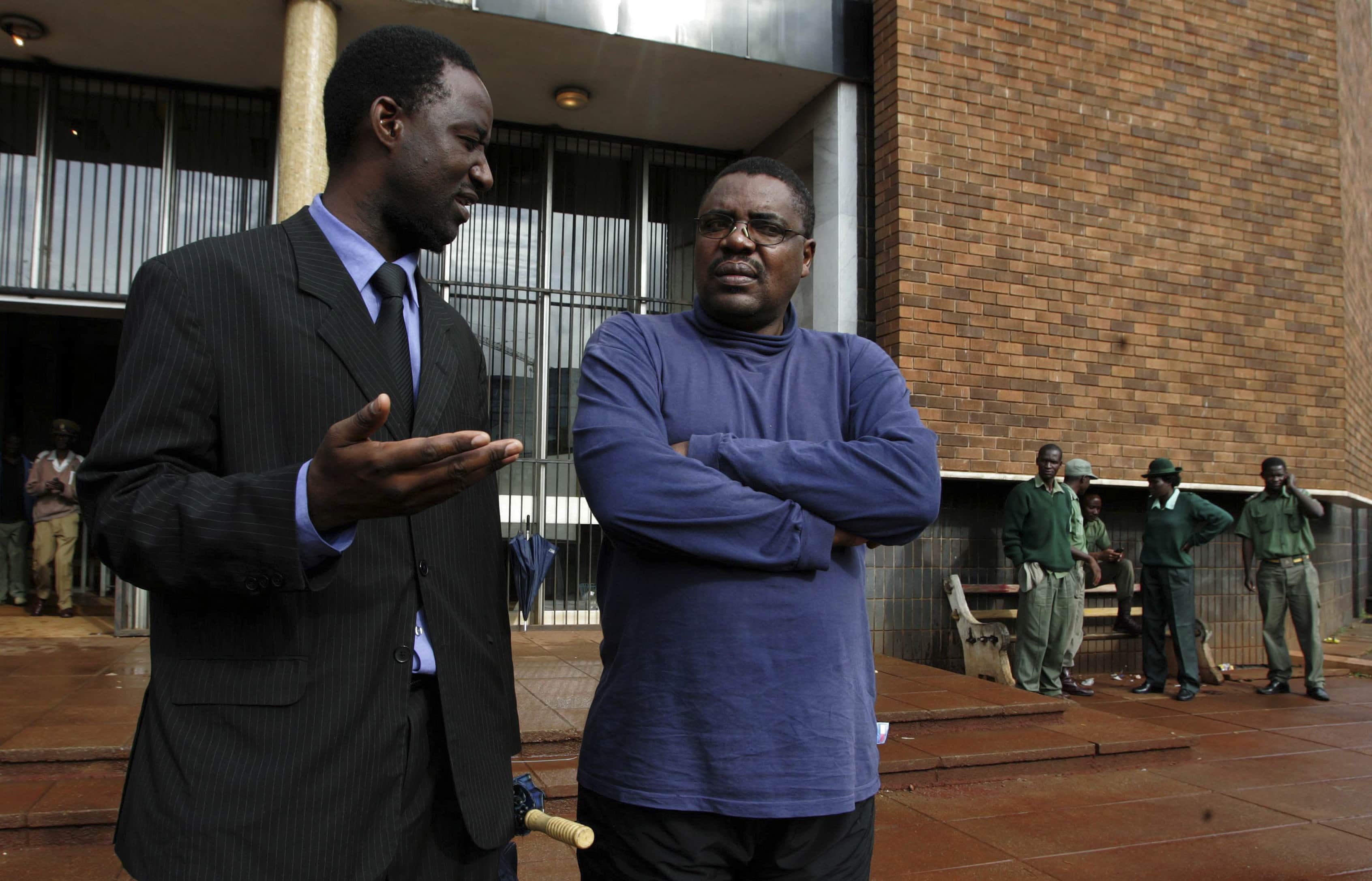 Nevanji Madanhire (C), editor of The Zimbabwe Standard Newspaper, talks to his lawyer Chris Mhike (L) as they leave the Harare Magistrates Court, 1 December 2010, REUTERS/Philimon Bulawayo