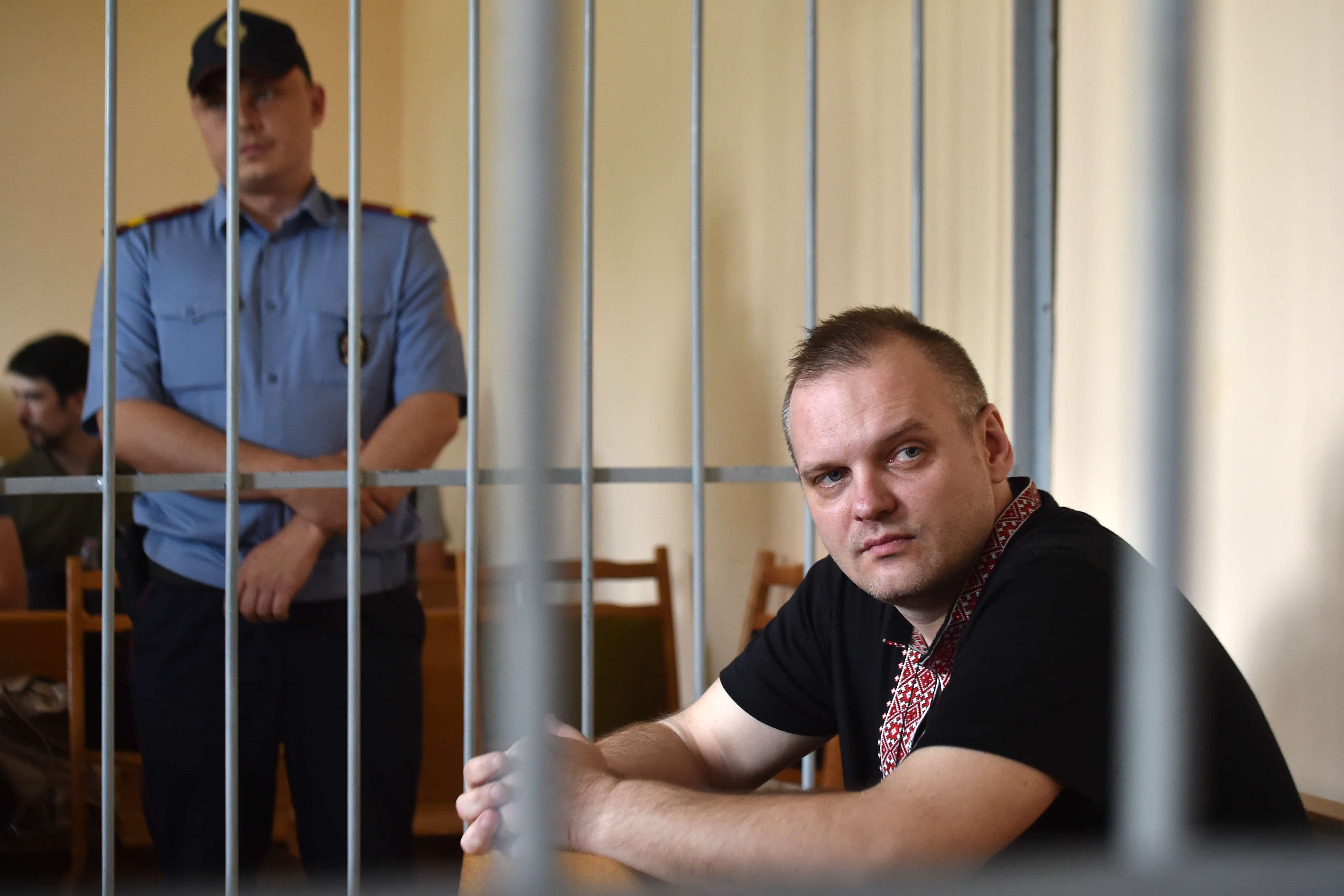 Independent journalist Zmitser Halko looks on as he sits in the defendants' cage on trial for allegidly using force against a police officer , Minsk, Belarus, 2018, SERGEI GAPON/AFP/Getty Images