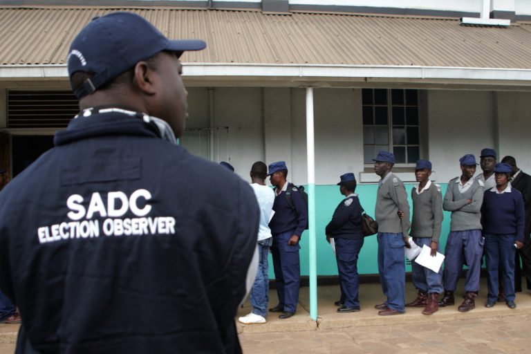 A SADC election observer looks on as Zimbabwe security forces queue to vote, in Harare, 14 July 2013, JEKESAI NJIKIZANA/AFP/Getty Images