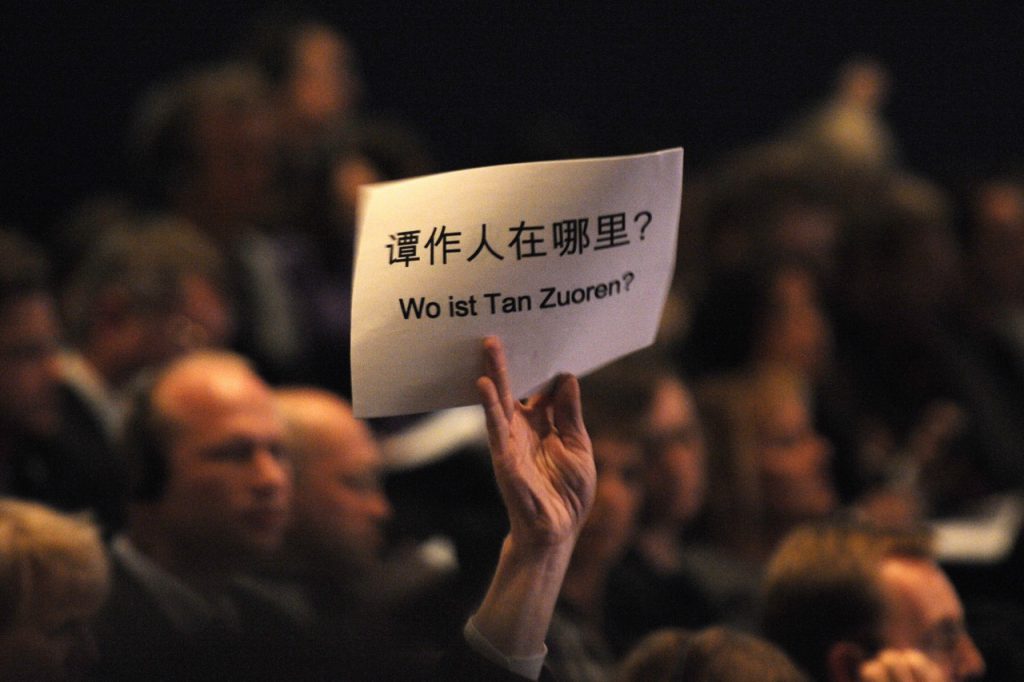 A man attending the Frankfurt Book Fair holds up a piece of paper inscribed with the words: 'Where is (Chinese activist and writer) Tan Zuoren?' during the speech of Chinese vice President Xi Jinping in Frankfurt, Germany, 13 October 2009, JOHN MACDOUGALL/AFP/Getty Images