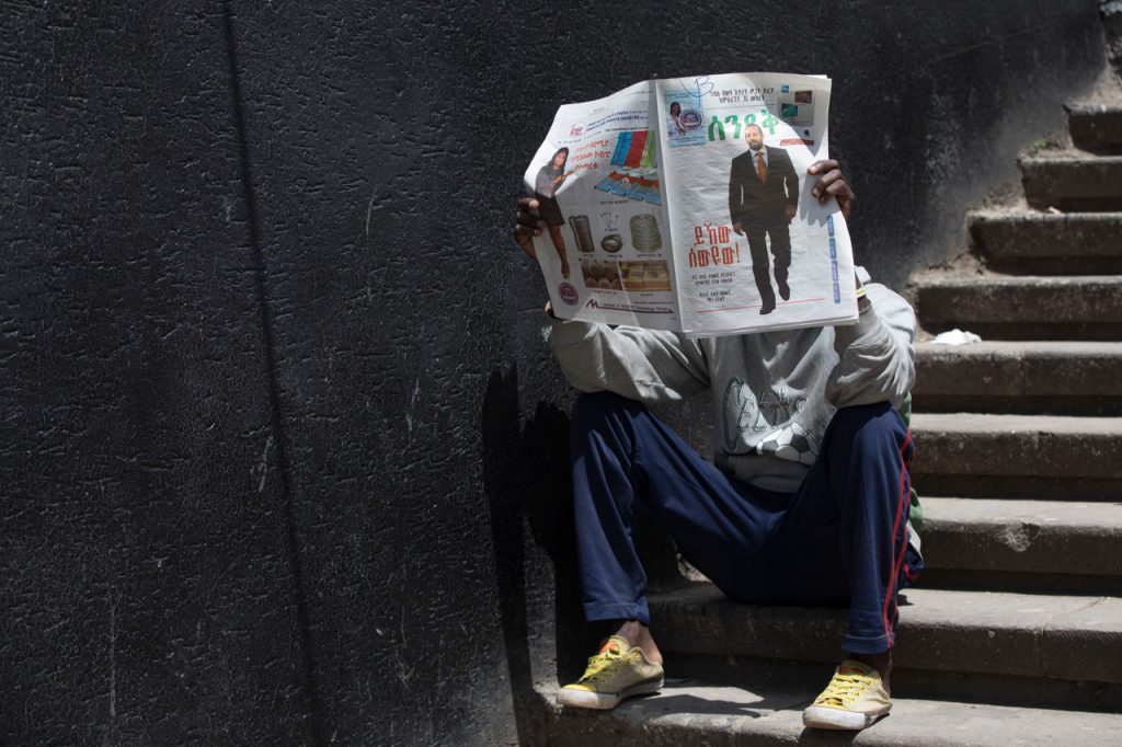 A man reads a newspaper with a story on Abiy Ahmed, newly elected leader of Ethiopia's ruling coalition, in Addis Ababa, 28 March 2018, ZACHARIAS ABUBEKER/AFP/Getty Images
