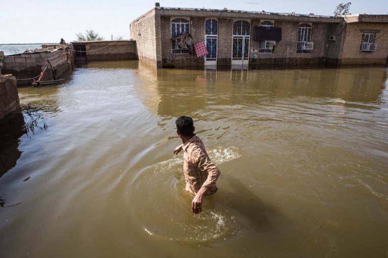 A man wades through flood water in a village in Khuzestan province, Iran, 13 April 2019, Xinhua/Ahmad Halabisaz via Getty Images