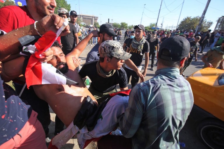 Iraqi men carry a wounded protester during a demonstration in Baghdad, 4 October 2019, AHMAD AL-RUBAYE/AFP via Getty Images