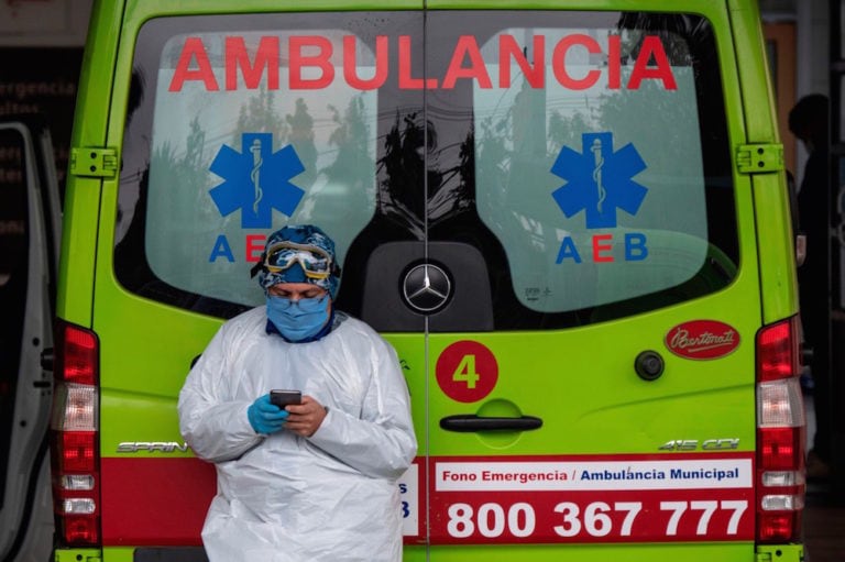 Un trabajador de salud chequea su teléfono al lado de una ambulancia, en Santiago, Chile, el 28 de mayo de 2020, MARTIN BERNETTI/AFP via Getty Images