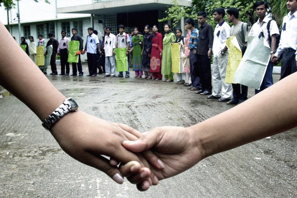 Members of the Dhaka University Journalism Division form a human chain during a demonstration to protest against the killing of Humayun Kabir Balu, in Dhaka, Bangladesh, 7 July 2004, STR/AFP via Getty Images