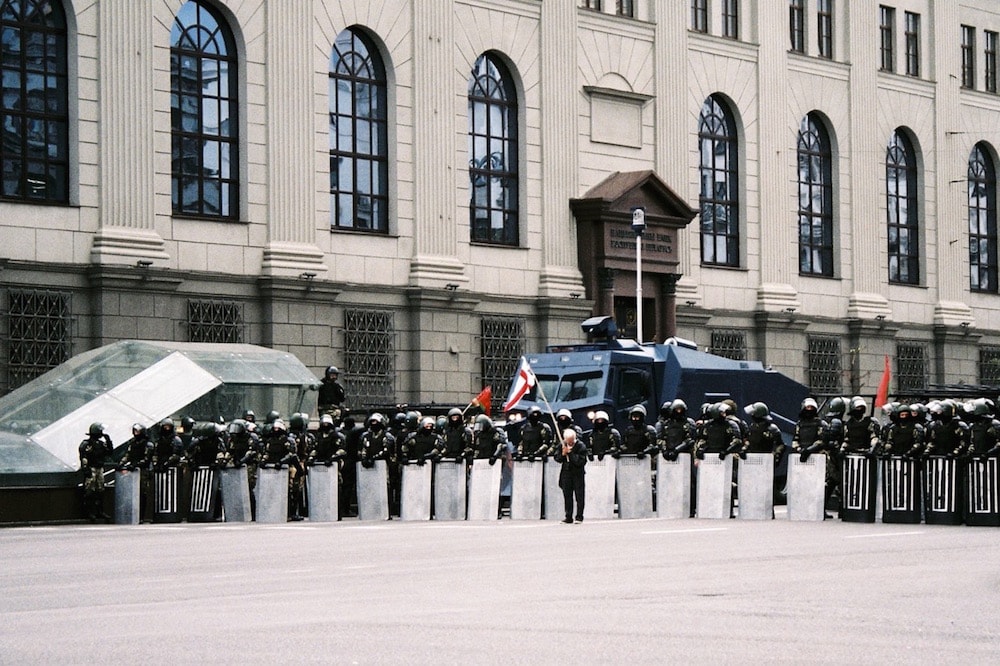 A protester stands in front of a line of riot police and a water cannon, Minsk, Belarus, 27 September 2020, Jana Nizovtseva/Flickr, CC0 1.0 Universal (CC0 1.0) Public Domain Dedication