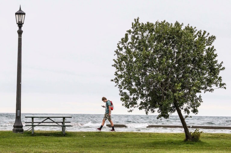 A young man looks at his smartphone while walking on a boardwalk by the lake, in Toronto, Ontario, Canada, 27 August 2019, Andrew Francis Wallace/Toronto Star via Getty Images