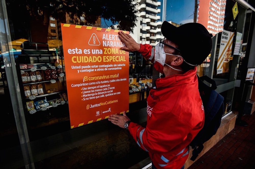 Un trabajador municipal cuelga un afiche sobre el Covid-19, en un área en Bogotá, Colombia, donde se habían registrado un gran número de casos, el 14 de mayo de 2020, JUAN BARRETO/AFP via Getty Images