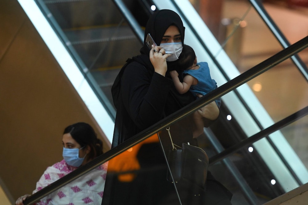 A woman holds her baby as she speaks on her mobile phone inside a shopping mall during a nationwide lockdown against COVID-19, Islamabad, Pakistan, 18 May 2020, on May 18, 2020, AAMIR QURESHI/AFP via Getty Images