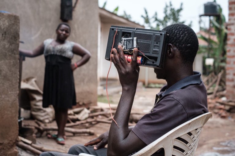 A Ugandan man listens to his radio for the final announcement of the presidential election results as his wife looks on, near the home of Presidential candidate Bobi Wine, in Magere, Uganda, 16 January 2021, YASUYOSHI CHIBA/AFP via Getty Images