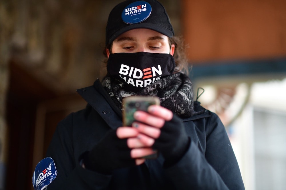 A young woman consults her smartphone for the next address to visit while canvassing for Democratic presidential nominee Joe Biden before the general election, Landsdowne, Pennsylvania, 1 November 2020, Mark Makela/Getty Images