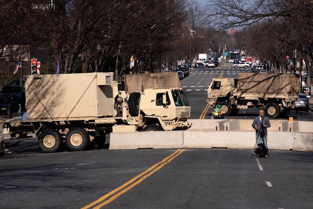 A TV reporter broadcasts in front of military vehicles near the U.S. Capitol, Washington, DC., 14 January 2021, Stefani Reynolds/Getty Images