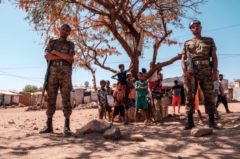Ethiopian Army soldiers stand in front of a group of children at the Mai Aini Refugee camp for Eritrean refugees amidst the conflict in Tigray, Ethiopia, 30 January 2021, EDUARDO SOTERAS/AFP via Getty Images