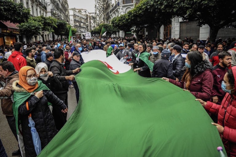 People carry a large Algerian flag during a protest held to mark the second anniversary of the mass 2019 'Hirak' demonstrations, in Algiers, Algeria, 22 February 2021, STR/picture alliance via Getty Images