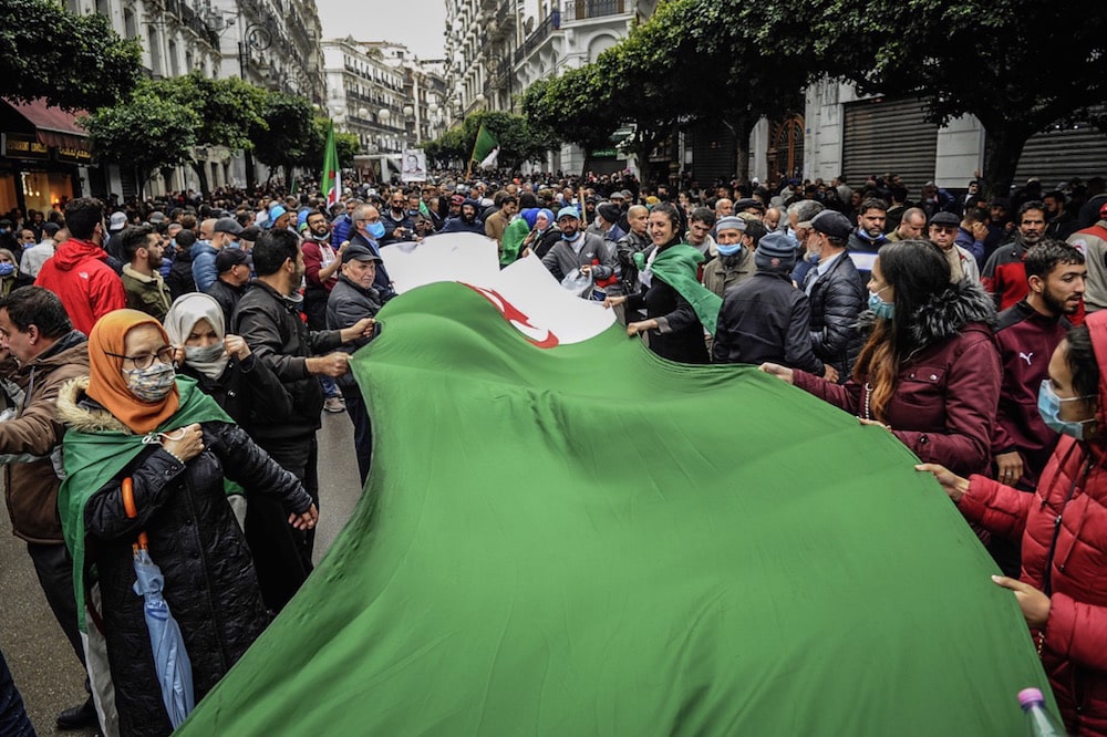 People carry a large Algerian flag during a protest held to mark the second anniversary of the mass 2019 'Hirak' demonstrations, in Algiers, Algeria, 22 February 2021, STR/picture alliance via Getty Images