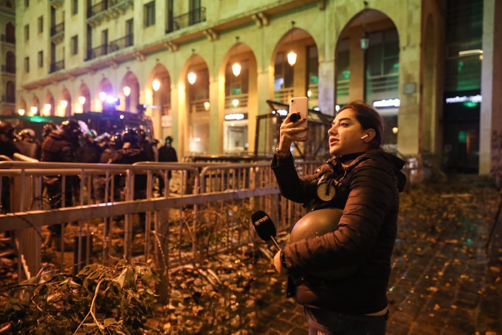 During a protest, a reporter uses a cell phone to film the scene by a security forces' barricade near the parliament, Beirut, Lebanon, 18 January 2020, ANWAR AMRO/AFP via Getty Images