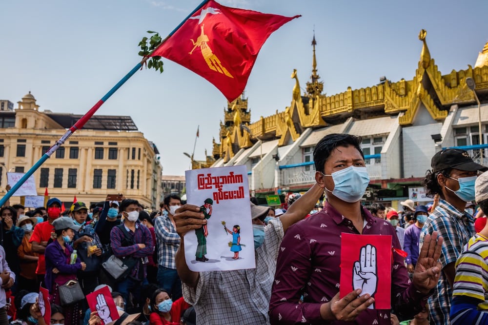 Protesters hold posters and flags during a march, in Yangon, Myanmar, 7 February 2021, a day after the military junta abruptly cut internet services and access to social media. Getty Images/Getty Images