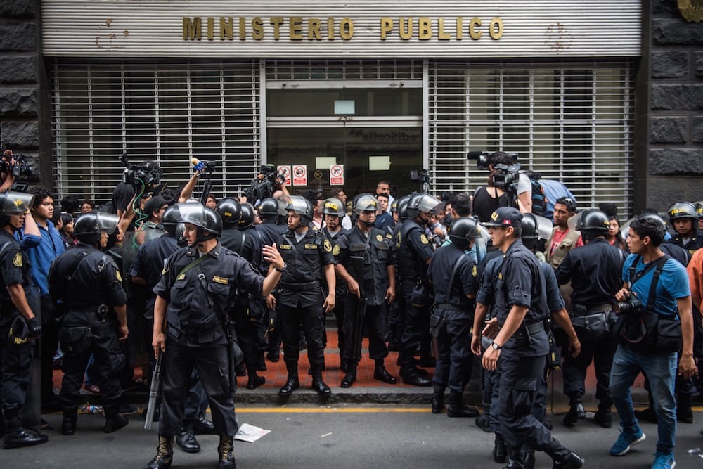 Unos policías y unos periodistas afuera de las oficinas del Ministerio Público, en Lima, Perú, el 28 de diciembre de 2017, ERNESTO BENAVIDES/AFP via Getty Images