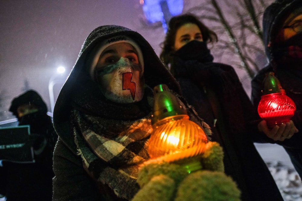 Members of the media hold candles and banners reading "Media with no choice" during a protest against the proposed advertising tax, labelled as "extortion", in front of the state owned broadcaster Telewizja Polska (TVP), in Krakaw, Poland, 10 February 2021, Omar Marques/Getty Images