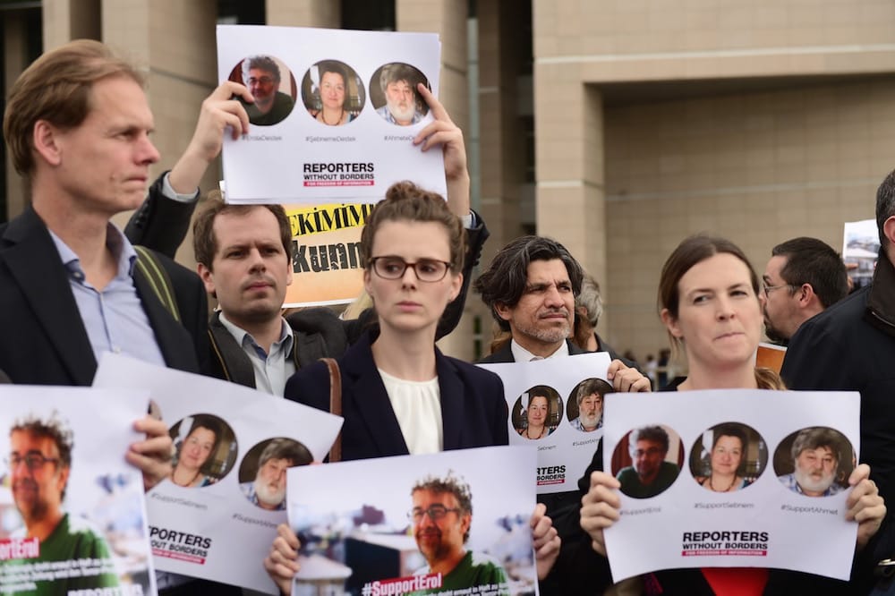 Journalists and activists hold pictures of the Turkey representative for Reporters Without Borders (RSF) Erol Önderoğlu (L), human rights defender Şebnem Korur Fincanci (C) and journalist Ahmet Nesin (R), in front of the Cagayan court house, Istanbul, Turkey, 8 November 2016, YASIN AKGUL/AFP via Getty Images