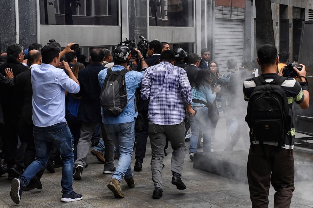 Unos periodistas y miembros de la oposición rodean al lider de la oposición Juan Guaidó, mientras que una bomba lacrimógena es lanzada, afuera del Palacio Federal, Caracas, Venezuela, el 7 de enero de 2020, YURI CORTEZ/AFP via Getty Images