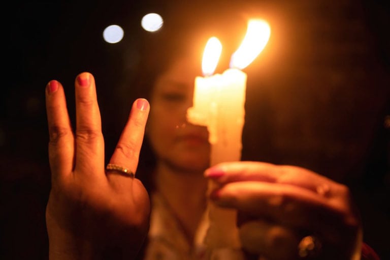 Kathmandu, Nepal, 31 March 2021. A protester holding a burning candle while making the three-finger salute attends a candlelight vigil for those who died in protests in Myanmar, Prabin Ranabhat/SOPA Images/LightRocket via Getty Images