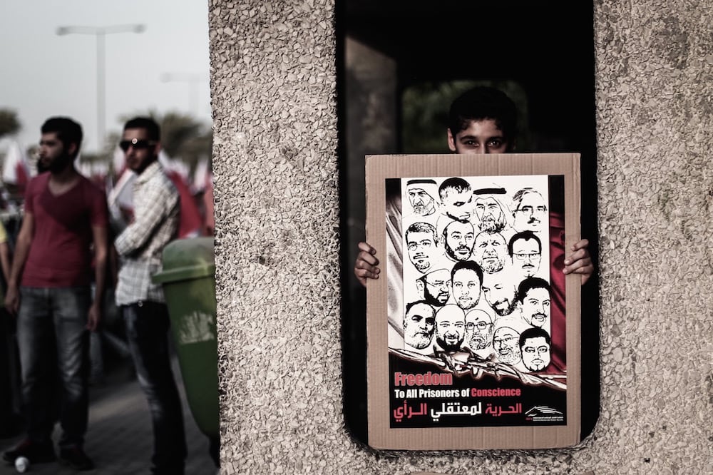 A young man holds a poster with images of prisoners of conscience, during an opposition pro-democracy demonstration, Duraz, Bahrain, 15 August 2014, Ahmed AlFardan/NurPhoto