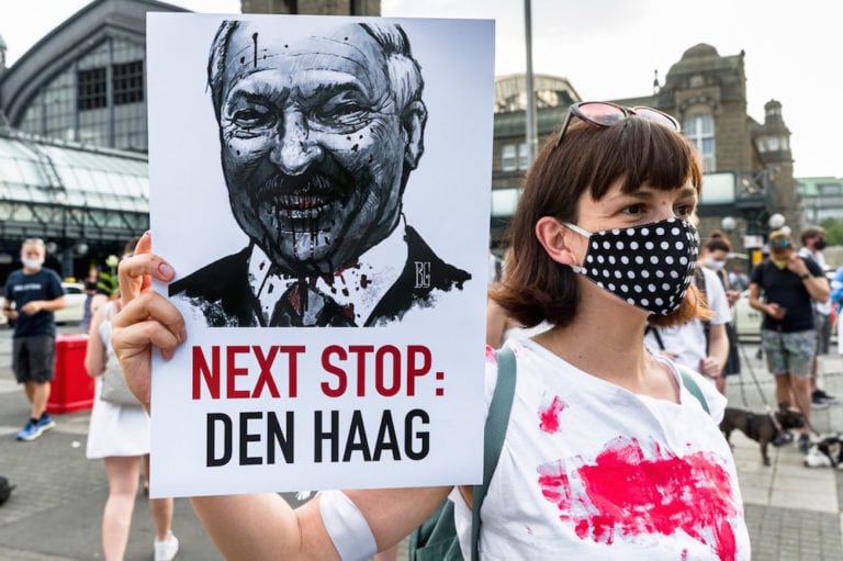 A woman holds a sign with an image of Belarusian President Lukashenko that reads "Next stop: The Hague" (referring to the International Criminal Court), during a solidarity protest by Belarusians living in exile, Hamburg, Germany, 15 August 2020, Markus Scholz/picture alliance via Getty Images