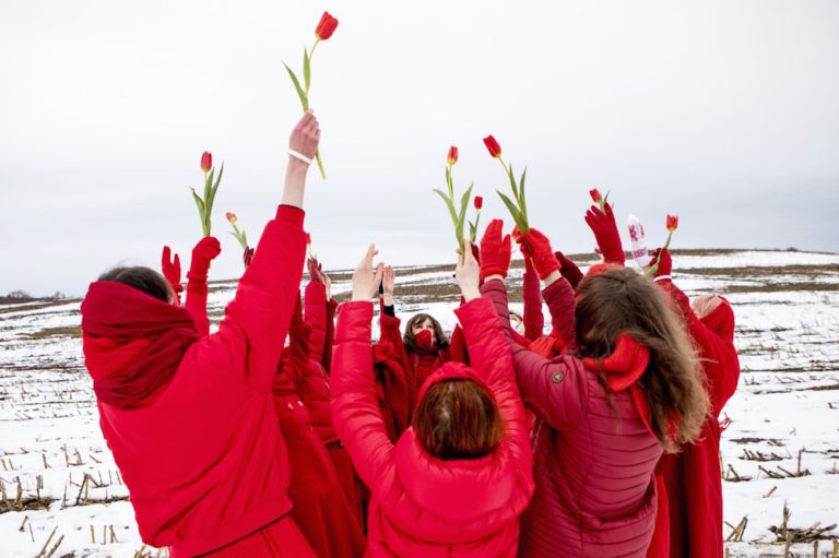 Mujeres vestidas de rojo bailan y sostienen tulipanes rojos mientras dan la bienvenida a la primavera durante una protesta contra los resultados de las elecciones presidenciales de Bielorrusia cerca de la aldea de Maloje Zapruddzie, 1ro de marzo de 2021, - / AFP a través de Imágenes Getty