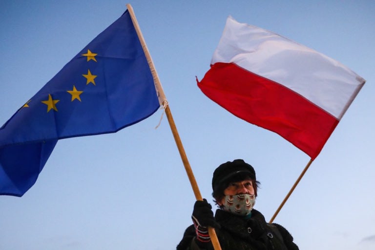 A woman holds Polish and EU flags while demonstrating against the Polish government's proposed media advertising tax which would impact private broadcasters, in Krakow, Poland, 12 February 2021, Beata Zawrzel/NurPhoto