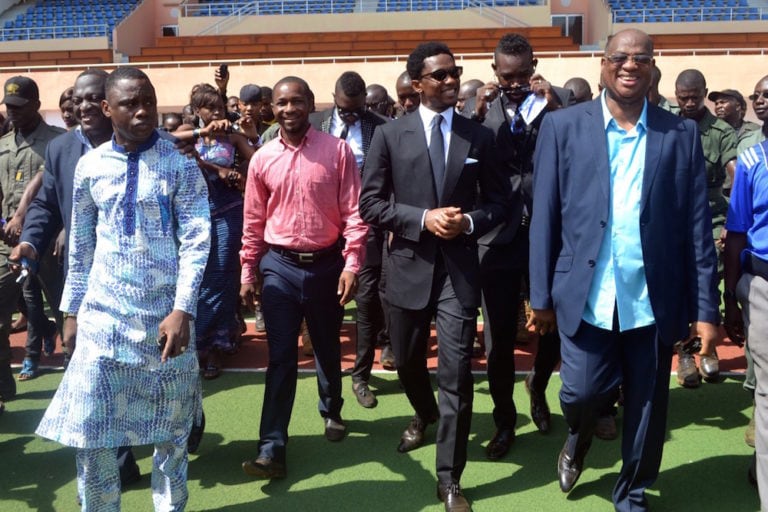 Guinea's Sports Minister at the time (L) and the then football federation president (R) in a stadium in Conakry, Guinea, during the visit of a Cameroonian football star, 23 February 2013, CELLOU BINANI/AFP via Getty Images